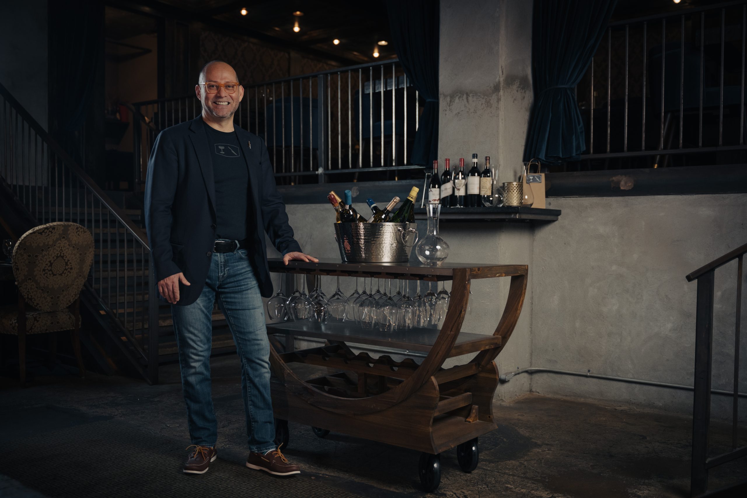 Pablo Aguilar beside a wine service cart with bottles and glassware