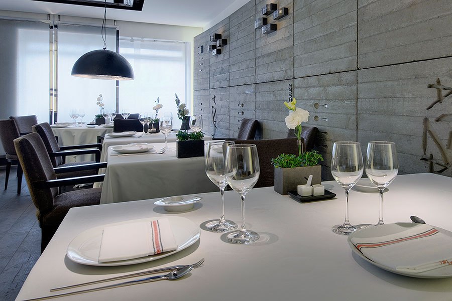 Restaurant tables set with white tablecloths, plates and wine glasses